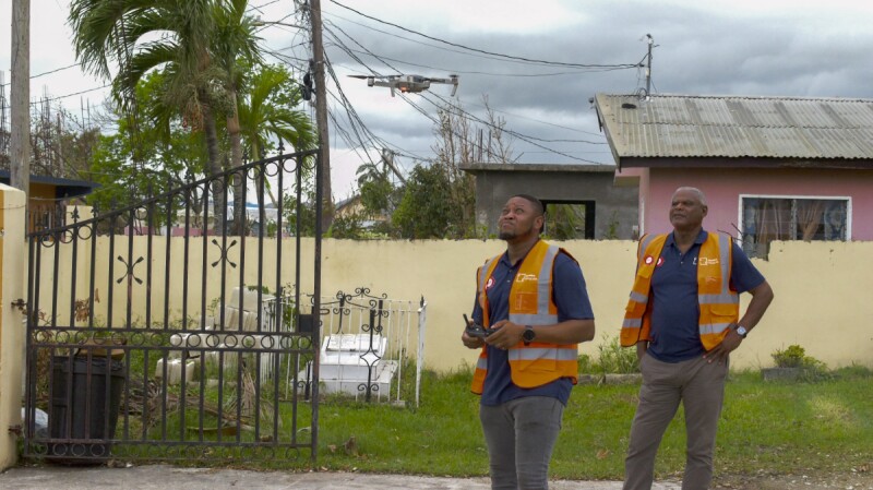 A Jamaica Flying Labs pilot and spotter track a drone as it begins a grid assignment over a storm-damaged neighborhood.